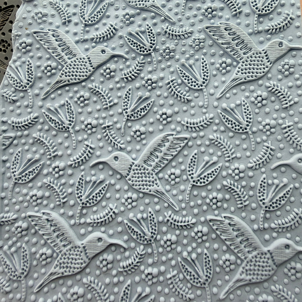 Hummingbird Flight rubber stamp impressed into polymer clay slab showing full all-over hummingbird and floral pattern